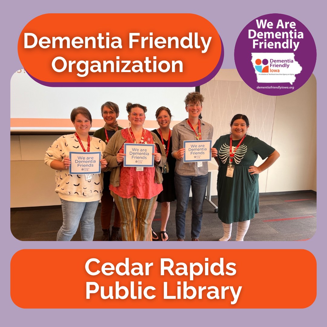 A group of people smile at the camera while holding certificates saying they are Dementia Friends.