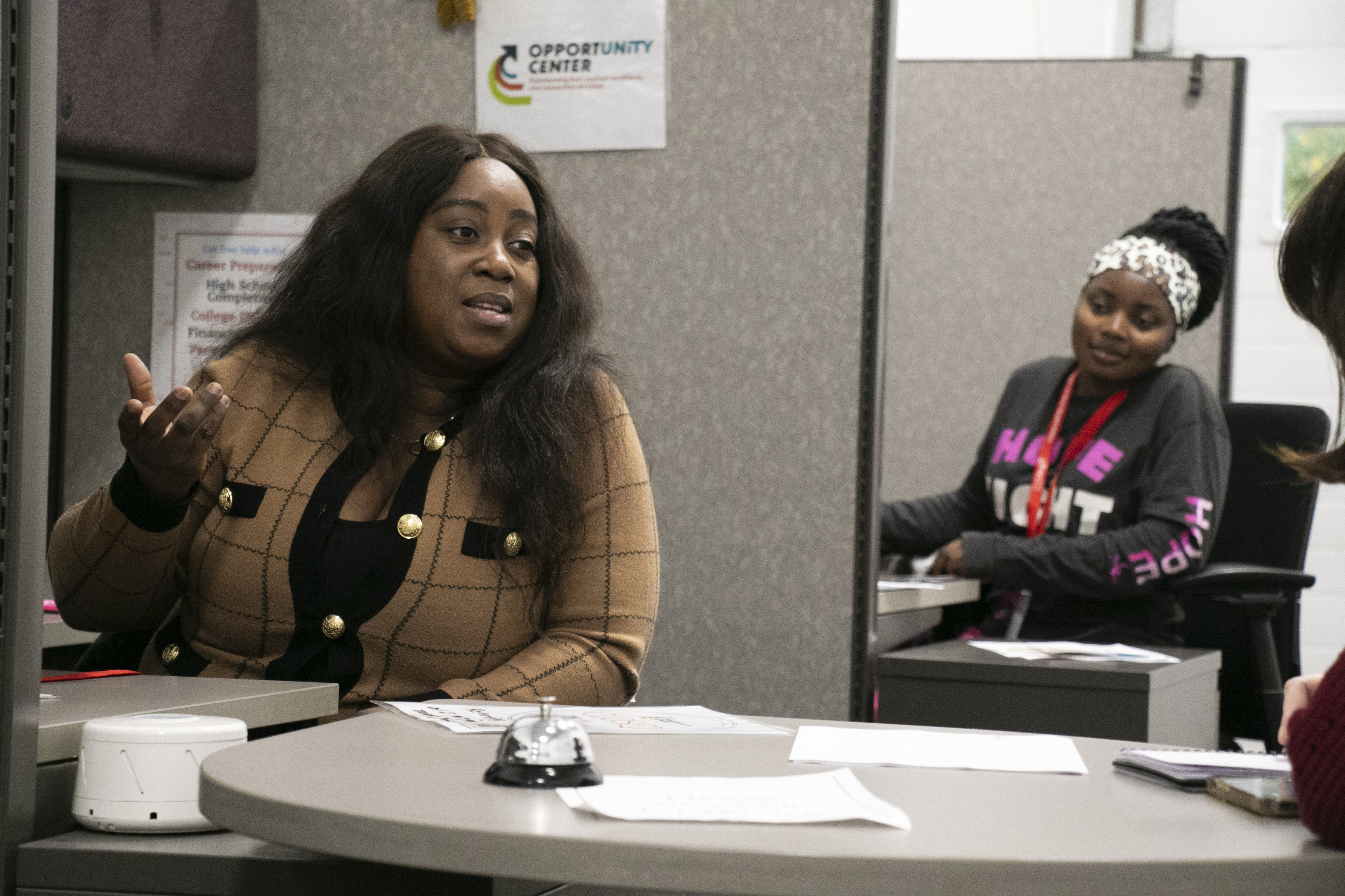 A woman gestures as she speaks while another woman looks on.