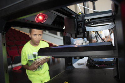 Young boy watching 3D printer