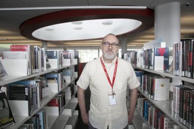 Wes Shirley wears a white shirt in front of book shelves.