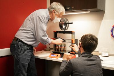 A man and woman lean over a 3D printer.