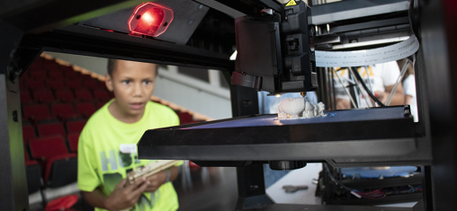 Young boy watching 3D printer