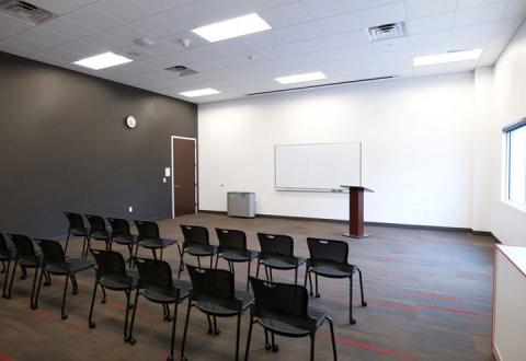 Community Room at Ladd Library featuring two rows of chairs facing screen and podium at front of room