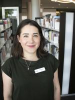 Ana McClain smiles at the camera in front of book shelves.